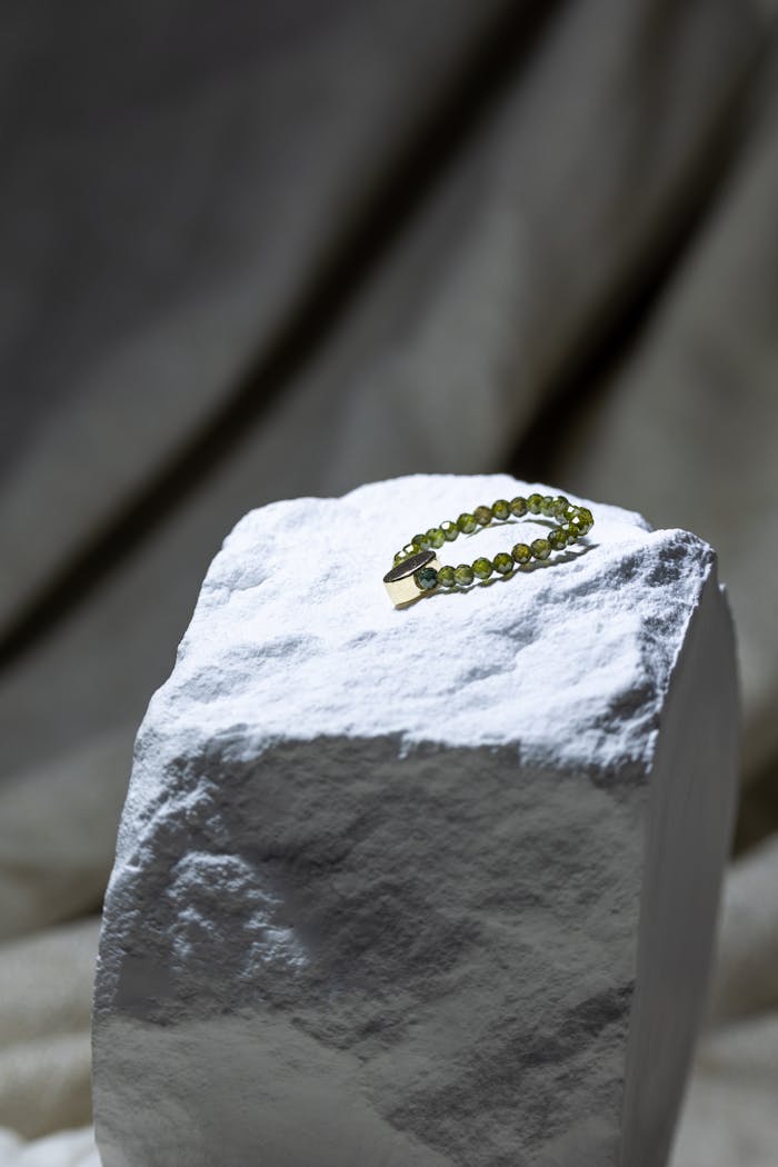 Sophisticated green gemstone bracelet showcased elegantly on a textured stone platform.